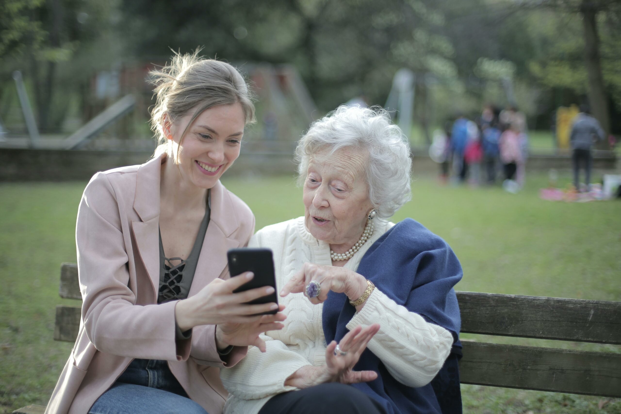 A caregiver showing her phone to an older adult with hearing loss.