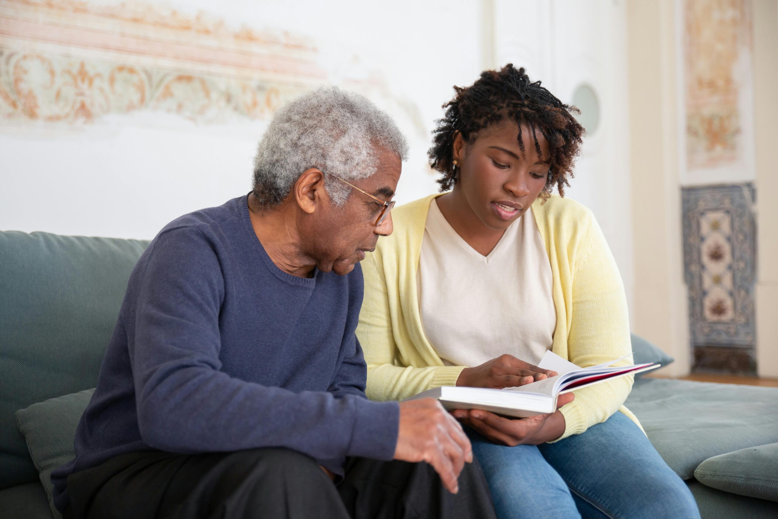 Older adult reading about the connection between hearing loss and dementia with his granddaughter.